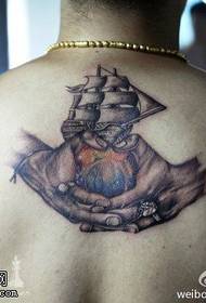 Les mains silencieuses tiennent le motif de tatouage de bateau