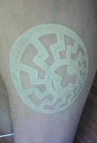 Valkoinen mustetatuointi pyöreällä logolla jalassa