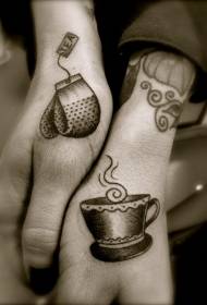 يد كوب رمادي من الشاي مع قفازات نمط الوشم