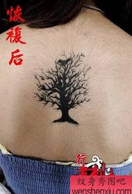 Ragazza con bellissimo albero totem e tatuaggio uccello sul retro