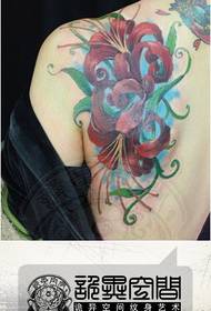 Leđa djevojke popularna je šarenim uzorkom tetovaže u obliku cvijeta.