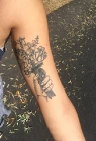 काळ्या राखाडी बिंदूच्या हातावर आणि वनस्पतींच्या फ्लॉवर टॅटूच्या चित्रावरील मुलीचा हात