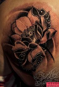 Un modello di tatuaggio di loto posteriore è condiviso dallo spettacolo di tatuaggi