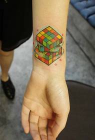Moda tal-polz femminili li tħares l-istampa mlewna tal-mudell tat-tatwaġġ Rubik's Cube