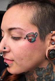 Mały tatuaż na filiżance na twarzy