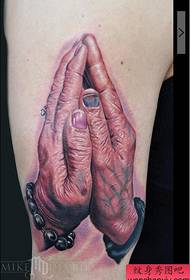 Një burrë i moshuar që lutet fotografi për tatuazhet me dorë në krahun e madh