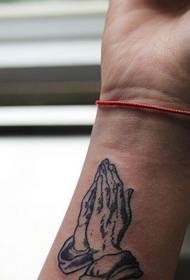 U travagliu di tatuaggio di a mano di a preghiera di u polso