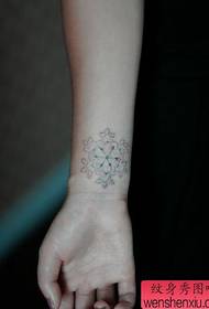 bijeli uzorak tetovaže snježne pahulje na zglobu djevojke