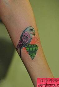 Braccio di ragazza con un colorato tatuaggio uccello e diamante