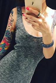 Trendi ljepotica ima lijepu sliku s cvjetnom tetovažom