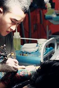 scena del tatuaggio del braccio del fiore dell'artista del tatuaggio