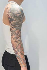 Un tatuaggio alternativo con braccio di fiori che unisce calamari ed elefanti
