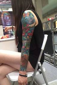 Dlhé vlasy-dievča s tetovaním tetovanie kvetinové zbrane