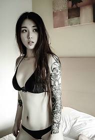 Bikini kageulisan nunjukkeun gambar panangan tattoo kembang di kamar pribadi