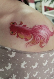 maliit na pattern ng tattoo ng goldfish na katabi ng babaeng clavicle