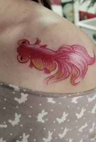 piccolo disegno del tatuaggio del pesce rosso accanto alla clavicola femminile