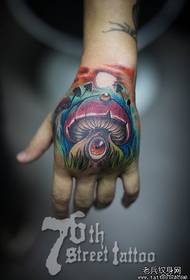 Un modello di tatuaggio fungo dagli occhi lunghi sul dorso della mano