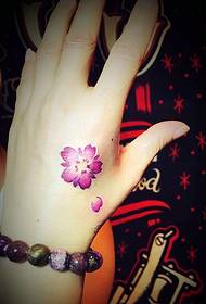 një lule e vogël e kuqe tatuazh tatuazhesh në anën e pasme të dorës