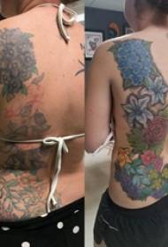 Tetovējums, kas aptver meitenes krāsainā tetovējuma ziedu tetovējuma attēla aizmugurē
