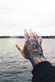 il dorso della mano sotto l'immagine del tatuaggio del sole picchi tutti