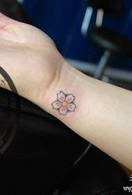 Pergelangan tangan perempuan adalah tato bunga sakura yang kecil dan indah