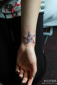 polso da ragazza con stella a cinque punte e motivo tatuaggio stellato
