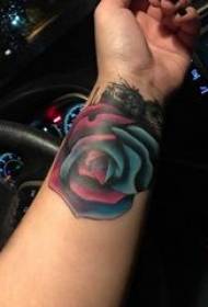 टैटू में लड़की की बांह पर रंगीन ढाल वाला टैटू गुलाब की तस्वीर है