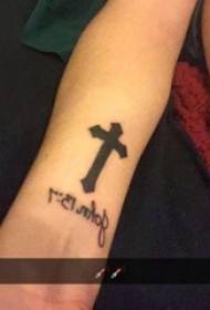 Braccio della ragazza sulla linea semplice nera inglese e foto del tatuaggio croce