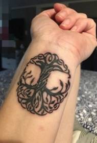 Le armi dei ragazzi sulle linee astratte in bianco e nero piantano le immagini del tatuaggio dell'albero della vita