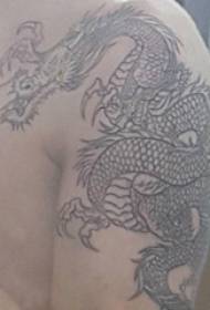 Tatuaż smoka totem męskiej ręki na czarnym obrazie smoka totem tatuaż