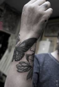 Рука мальчика на чёрной колющей картинке с изображением бабочки