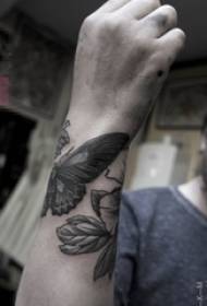 Braccio del ragazzo sul nero che punge la piccola foto del tatuaggio della farfalla animale