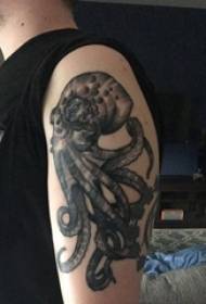 Juodos aštuonkojo tatuiruotės vyriška ranka ant juodo aštuonkojo gyvūno tatuiruotės paveikslėlio