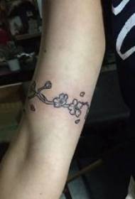 Tatui il braccio della bambina di fiori sull'immagine nera del tatuaggio del piccolo fiore