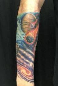 Braccio del ragazzino del tatuaggio cosmico sulla foto del tatuaggio del pianeta cosmico