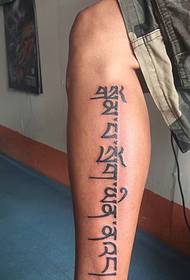 Semplice tatuaggio del tatuaggio sanscrito sulla parte esterna del polpaccio