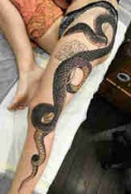 Čūskas tetovējuma attēla zēna augšstilbs uz čūskas tetovējuma attēla