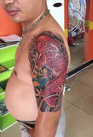 Ølmage fremhever den røde snapper-tatoveringen på mannens arm