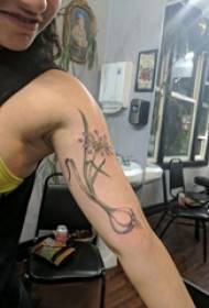 U bracciu di mudellu di tatuaggi di Daffodil nantu à a stampa di tatuaggi di narcisi grigiu neru