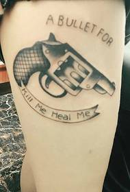 una pistola sulla parte esterna della coscia con un disegno del tatuaggio inglese