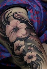 Drie bloemtattoos op de vrouwelijke arm