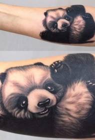 Црно-бела слатка мала панда која се игра са тетоважама на полеђини руке