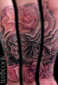 Lijepa ruža u boji ruke s tetovažom ljudske lubanje
