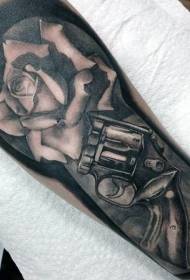 Armgrå realistisk gammal revolver och rosatatuering