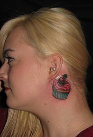 прилично женско лево уво зад слатката слика за тетоважа со мала торта