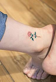 малка снимка с татуировка на прясно цвете, скрита на стъпката на двойка