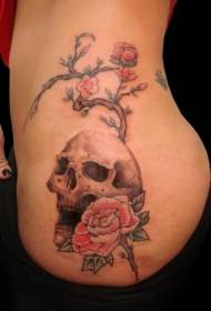 Svajinga spalvota kaukolė juosmens pusėje ir žydinčio medžio tatuiruotės modelis
