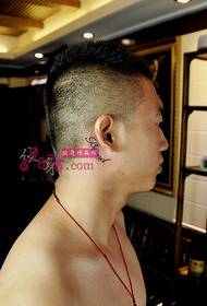 Чоловіче вухо за невеликою свіжою англійською татуюванням