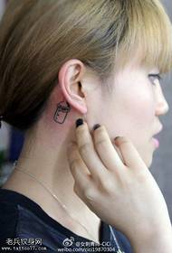 telinga perempuan di belakang pola tato botol kecil segar