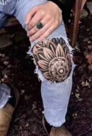 yon seri tatoo pèsonalize ap travay sou jenou an
